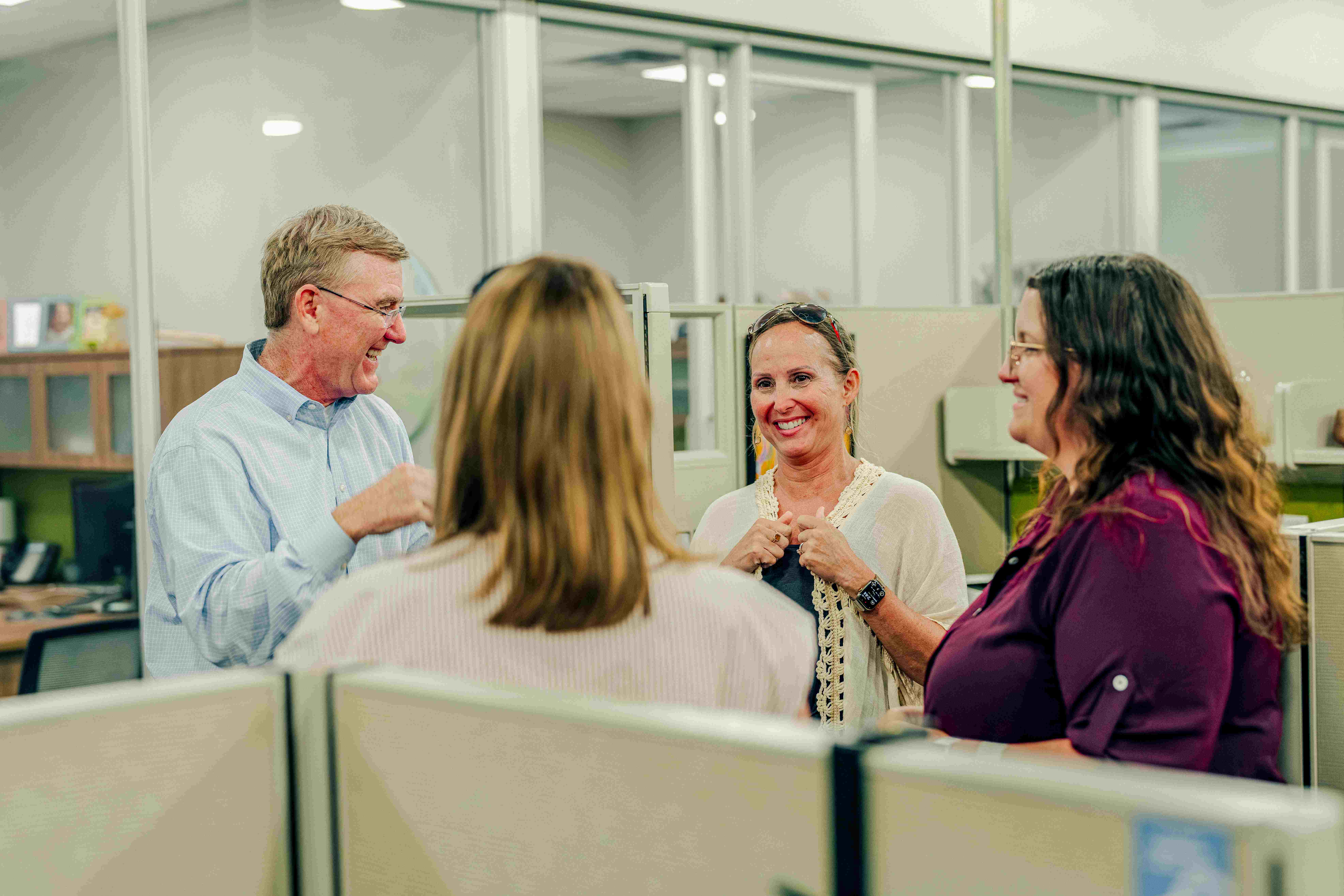 Four coworkers conversing in an office.